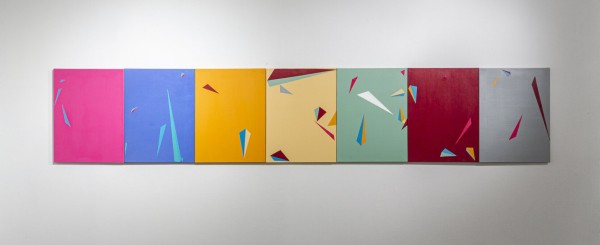 <span class='caption-artist'>Ezra Benus</span>, <span class='caption-title'>Sun/Moon</span>, <span class='caption-year'>2020</span>, <span class='caption-medium'>Acrylic on canvas</span>, <span class='caption-dimensions'>Image Description: Seven canvases are hung directly next to each other, forming one large horizon line of paintings. Each has one main background color, from left to right: pink, blue, orange, yellow, sage green, maroon, and grey. The palette of the background colors mixed and used throughout the canvases create colorful compositions with a variety of triangles painted on them, giving an impression that they are floating and crashing all over, spilling onto the edges of the neighboring canvases.</span>
