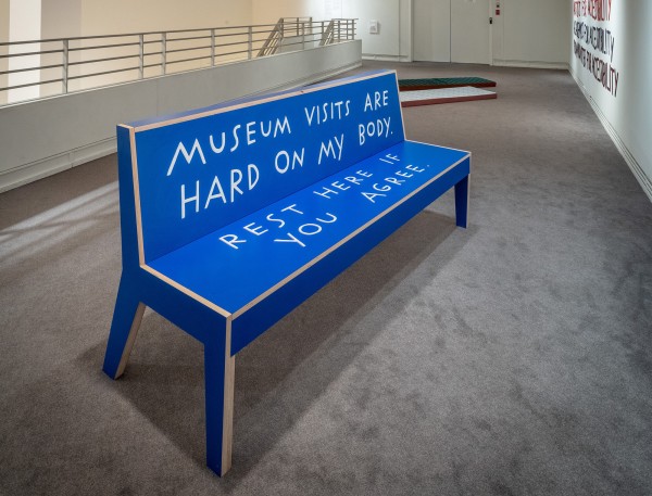 <span class='caption-artist'>Shannon Finnegan</span>, <span class='caption-title'>Do You Want Us Here or Not?</span>, <span class='caption-year'>2020</span>, <span class='caption-medium'>Baltic birch, poplar wood, plastic laminate</span>, <span class='caption-dimensions'>Image Description: A bright blue bench with hand-lettered text that reads, “Museum visits are hard on my body. Rest here if you agree.”</span>